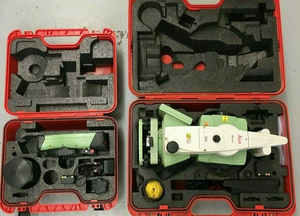 image of a used leica ts12 robotic total staion along side a cs15 field controller, they are place inside of their individual carry cases